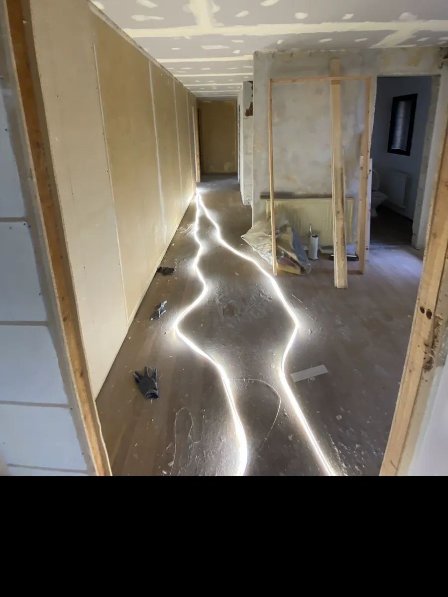 Gang under renovering med rå gipsvægge, afstivninger og bart gulv