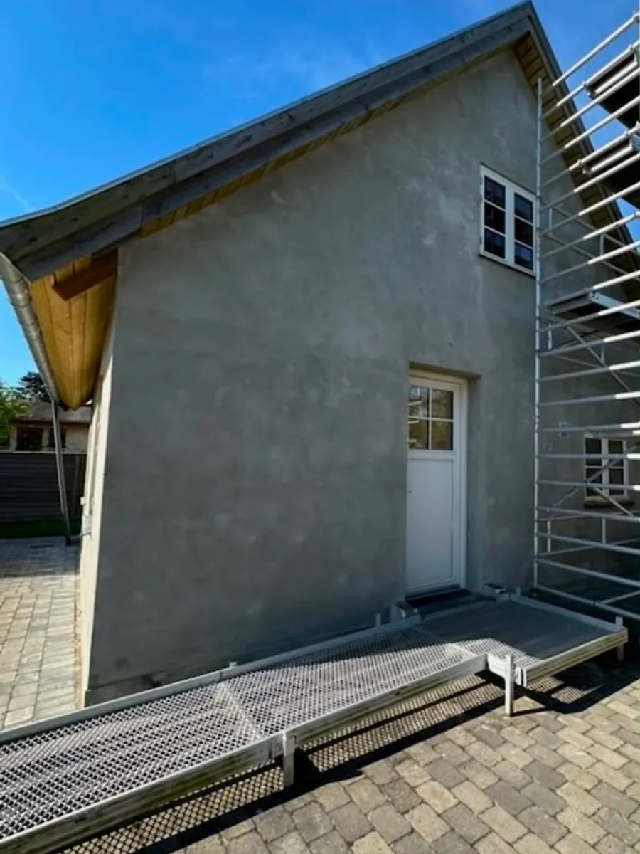 Gavl med råt, ubehandlet puds og stillads sat op før malerarbejdet