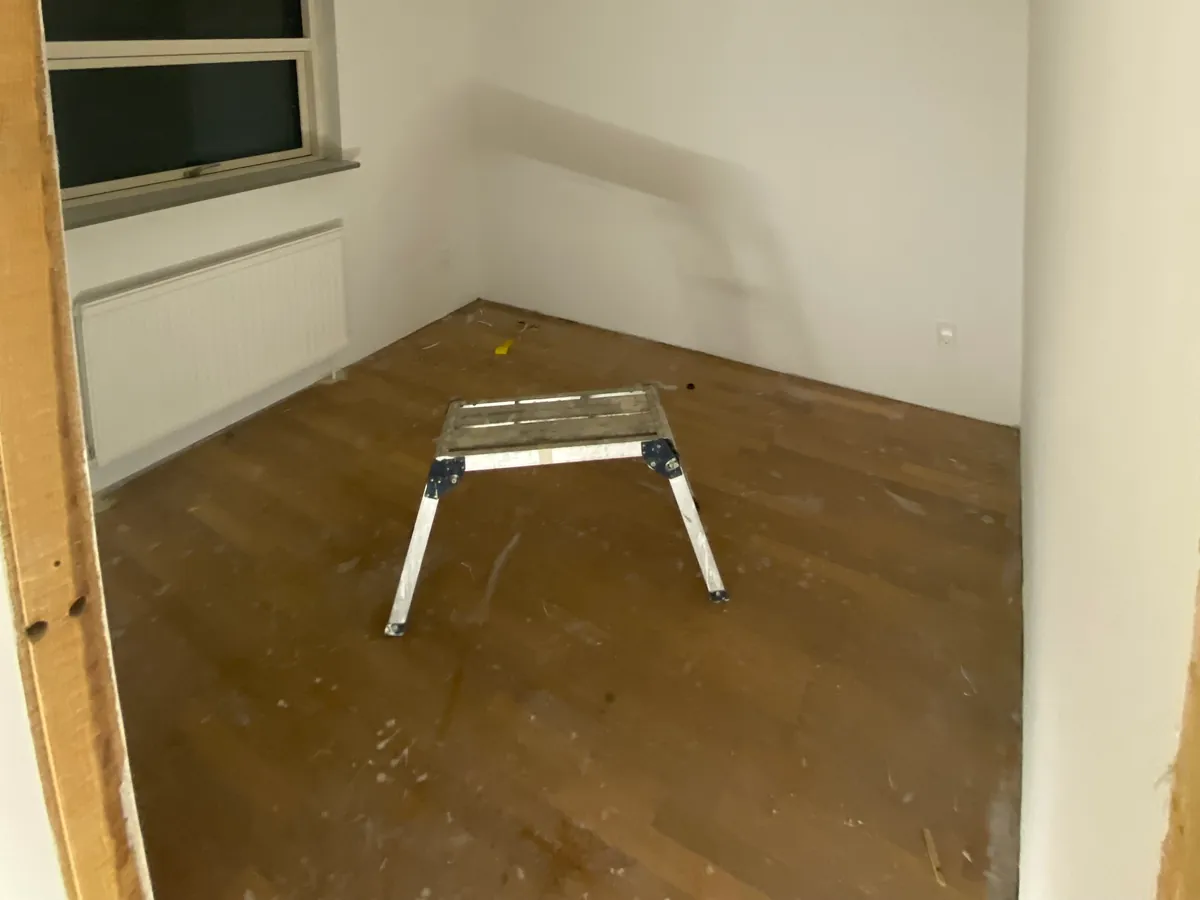 Tomt værelse med nymalede hvide vægge og loft, og et gulv der endnu ikke er lagt